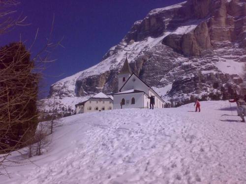 a church on the side of a snow covered mountain at Miniappartamento Dolomiti in Selva di Cadore
