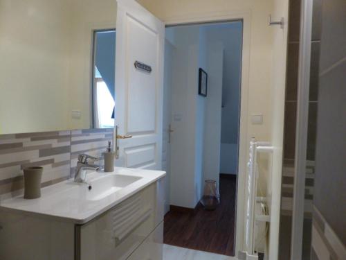 uma casa de banho com um lavatório, um espelho e um chuveiro em LE RUBAN BLEU FACE A LA MER em Arromanches-les-Bains