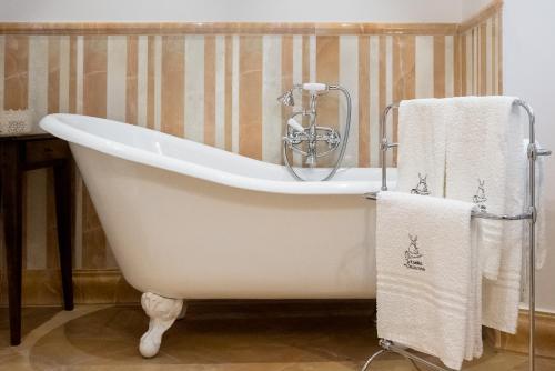 uma banheira branca na casa de banho com toalhas em Le Camere Del Ceccottino em Pitigliano