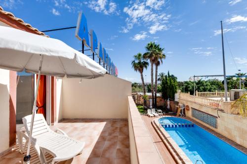 eine Terrasse mit einem Sonnenschirm und einem Pool in der Unterkunft Apartamentos Atlas in Torrevieja