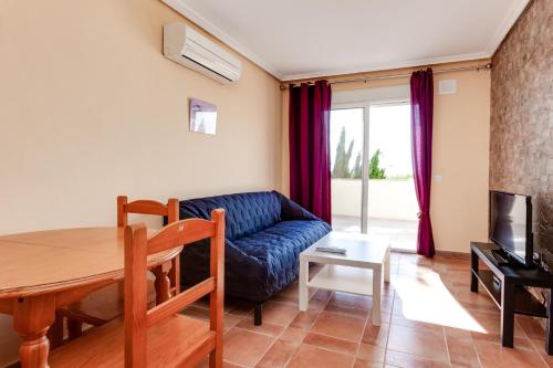 a living room with a blue couch and a table at Apartamentos Atlas in Torrevieja