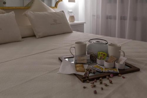 a tray with cups and cookies on a bed at Petra Bianca in Torre San Giovanni Ugento