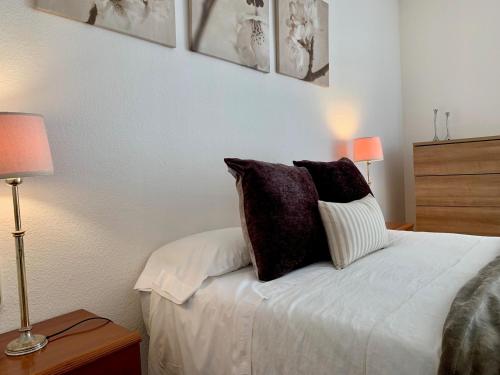 Apartamento Puerto Miramar في كامبريلس: غرفة نوم بسرير ومخدات ومصباحين