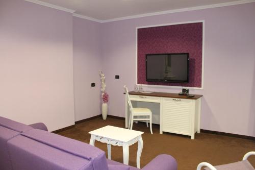 a living room with a purple couch and a tv at Regina Maria Spa Design Hotel in Balchik