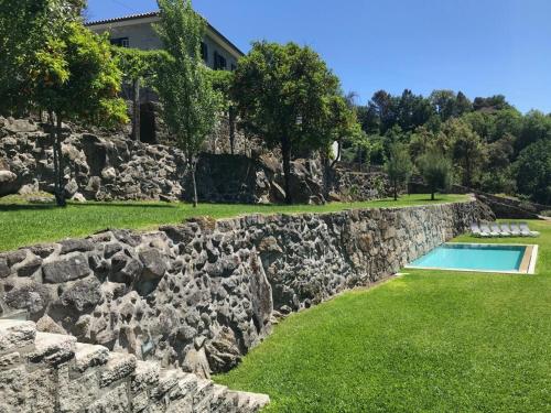 una pared de piedra junto a la piscina en Quinta Parque Nacional Peneda Geres en Paradamonte