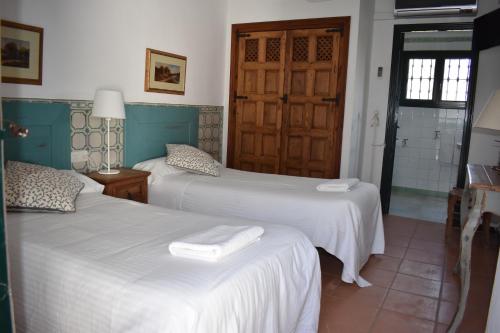 a bedroom with two beds with white sheets at Lince Casa Rural in El Rocío