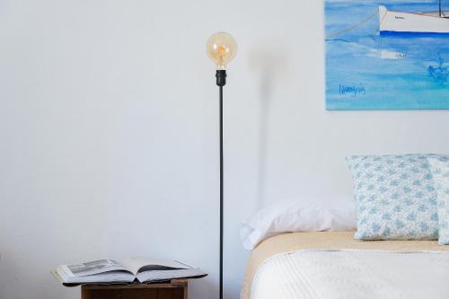 a floor lamp next to a bed with a book at HOTEL ANHEL in Ferreries