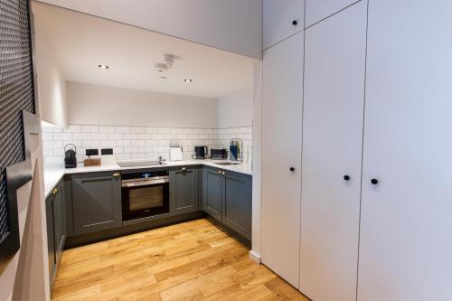 a kitchen with white cabinets and a wooden floor at Linton Collection - Blackfriars Lofts in Edinburgh