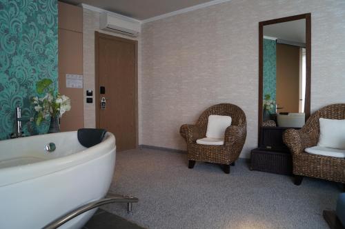 a bathroom with a tub and two chairs and a mirror at Regina Maria Spa Design Hotel in Balchik