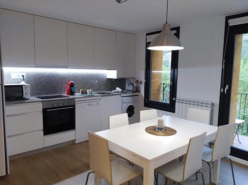 a kitchen with white cabinets and a table and chairs at Ca de Géraldine in El Pont de Suert
