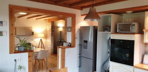 eine Küche mit einem Kühlschrank aus Edelstahl und einem Tisch in der Unterkunft Gîte Noa in Xonrupt-Longemer