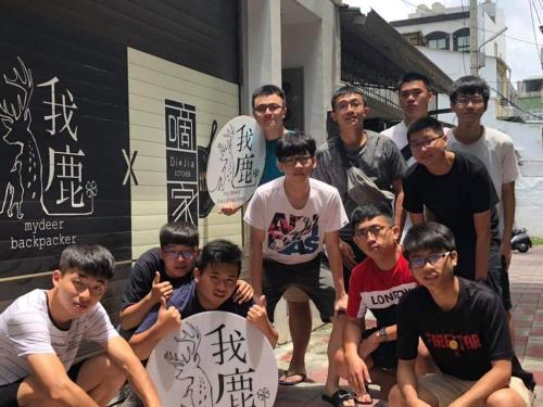 a group of young men posing in front of a building at mydeer backpacker in Tainan