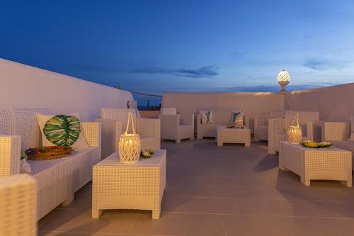 a patio with wicker chairs and tables with lights at Petra Bianca in Torre San Giovanni Ugento