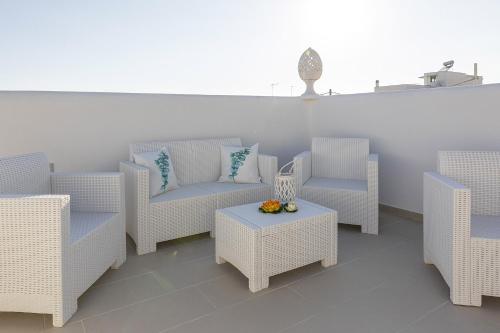 a patio with white wicker chairs and a table at Petra Bianca in Torre San Giovanni Ugento