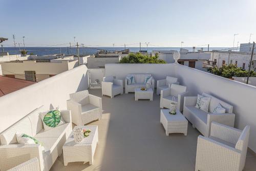 d'un balcon avec des chaises blanches et des tables sur le toit. dans l'établissement Petra Bianca, à Torre San Giovanni