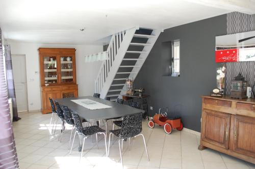 a dining room with a table and chairs and a staircase at La Mansarde in Magny-en-Bessin