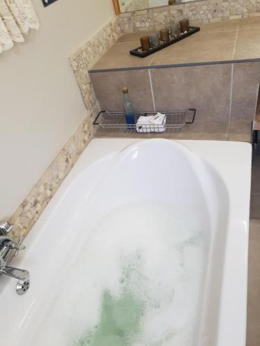 a bath tub with water in it in a bathroom at Dilisca Guesthouse in Durbanville