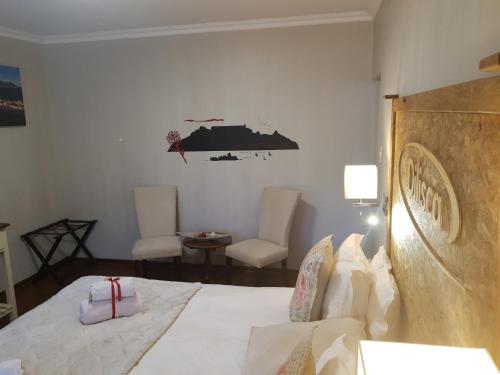 a bedroom with a bed and two chairs at Dilisca Guesthouse in Durbanville
