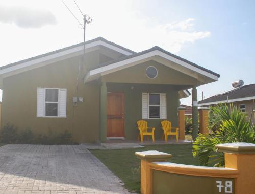 una casa verde con dos sillas delante en Draxhall Counytry Club Stays, en Mammee Bay