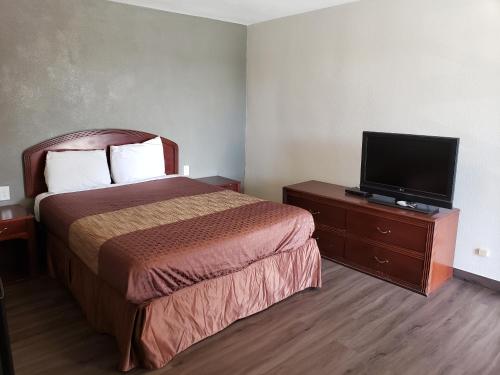 a hotel room with a bed and a flat screen tv at Classic Inn and Suites in El Centro
