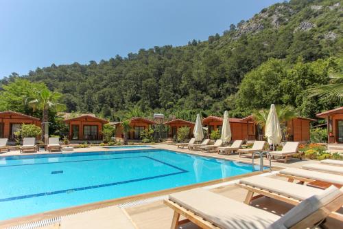een zwembad in een resort met stoelen en een berg bij Dolunay Apart Hotel in Cıralı
