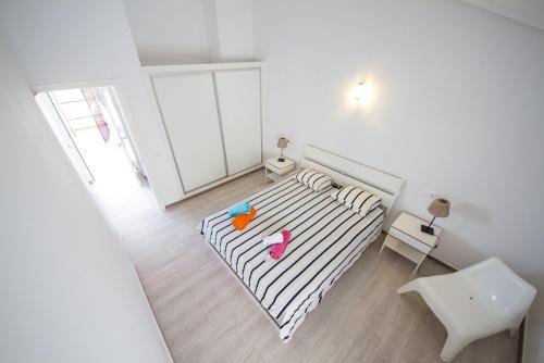 アデへにあるhome canariasの白い小さな客室で、ベッド1台と椅子が備わります。