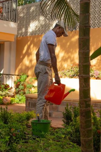 a man holding a red pail in a garden at Hotel La Gloria in Mompos