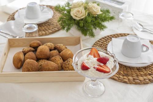 a table with a tray of pastries and a bowl of fruit at Petra Bianca in Torre San Giovanni Ugento
