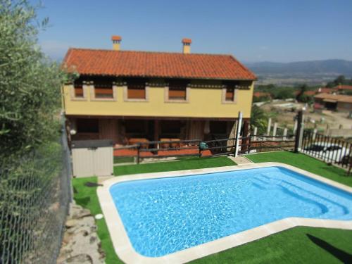 a swimming pool in front of a house at Casas Rurales La Dehesa in Casas del Monte