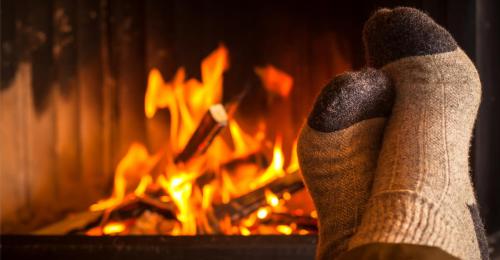 a person with their feet up in front of a fire at Alpenappartement Kleiner in Tannheim