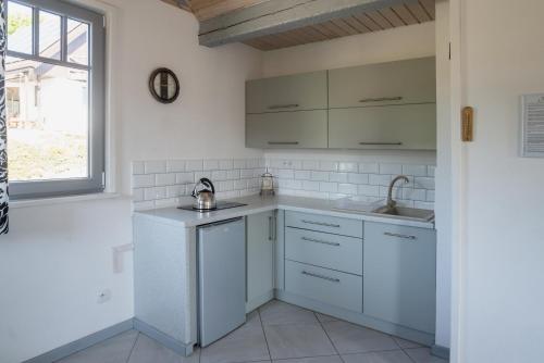 a kitchen with white cabinets and a sink and a window at Domek Skowronek in Szczytna