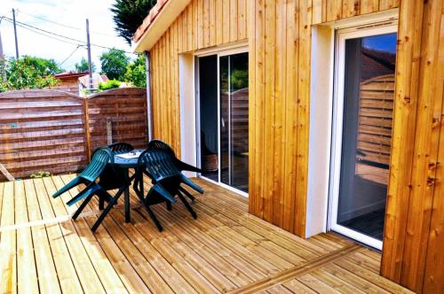 une terrasse en bois avec une table et des chaises. dans l'établissement La Hume Vacances, à Gujan-Mestras