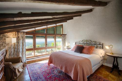 a bedroom with a bed and a large window at Masia Can Pou in Canet de Adri