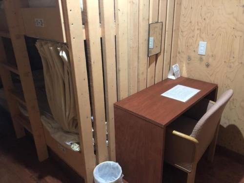 un escritorio de madera con una silla junto a una pared de madera en Guesthouse Wanokaze mix domitory / Vacation STAY 32202, en Otaru