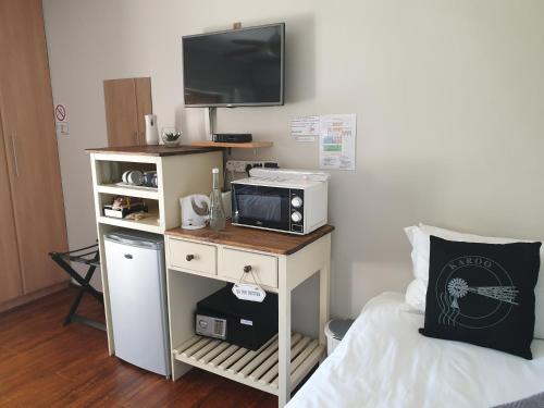 a room with a bed and a microwave and a tv at Dilisca Guesthouse in Durbanville