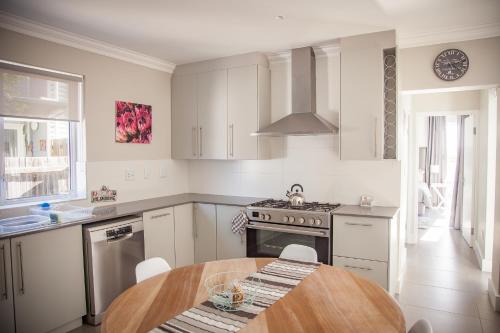a white kitchen with a wooden table in it at Sea-renity in Yzerfontein
