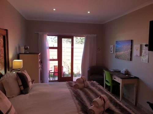 a bedroom with a bed and a desk and a window at Dilisca Guesthouse in Durbanville