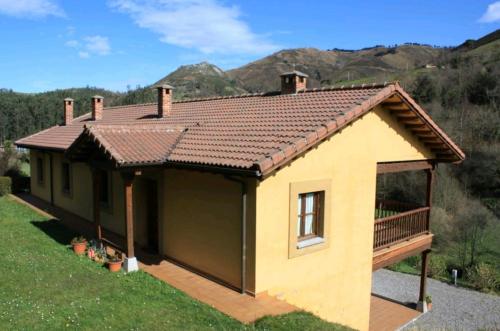 uma pequena casa amarela com telhado em Casa Rural La Llosica em Ribadesella