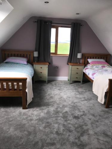 a attic bedroom with two beds and a window at Tigh a Chabar in Lochaline