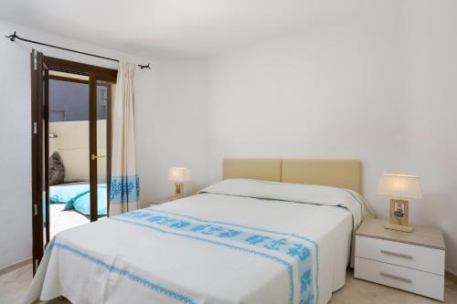 a white bedroom with a bed and a mirror at Le Maree Apartments in Cannigione