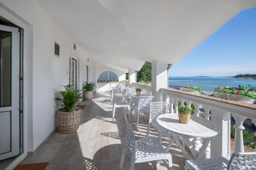 a balcony with tables and chairs and the ocean at Apartments and rooms Jakić in Medulin