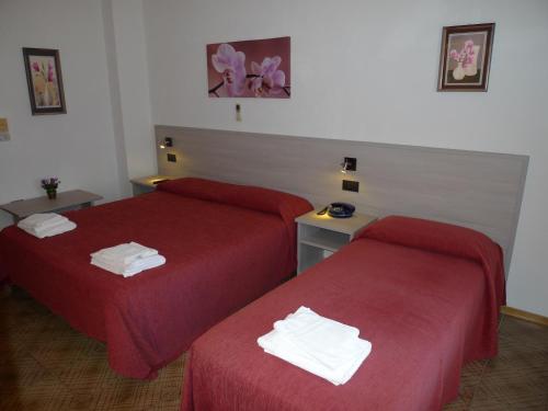 two beds in a hotel room with red sheets at Hotel Alexander in Tropea