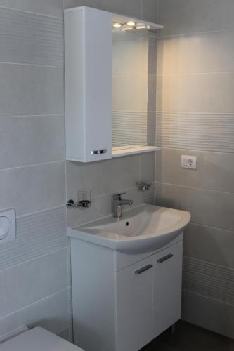 a white bathroom with a sink and a mirror at Medulinka apartments in Medulin