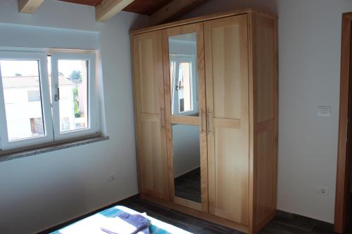 a wooden cabinet in a room with two windows at Medulinka apartments in Medulin