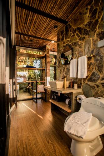 a bathroom with a toilet and a stone wall at Bio Habitat Hotel in Armenia