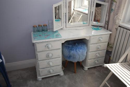 a dresser with a mirror and a blue feather under it at Weymouth Vegan B&B in Weymouth