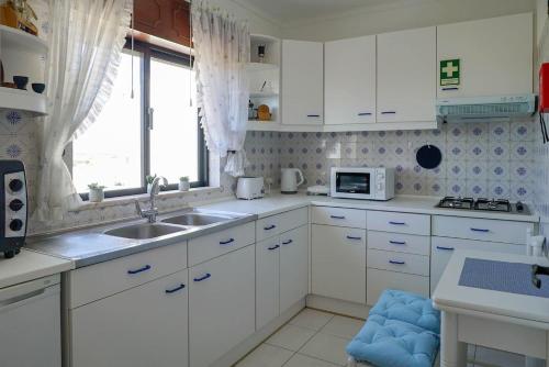 a kitchen with white cabinets and a sink and a window at Studio Apartment with Sea View & Fibre Internet in Albufeira