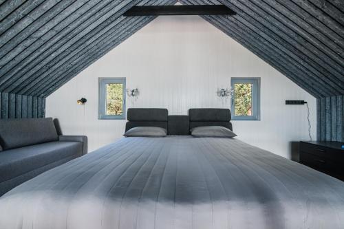 een groot bed in een kamer met 2 ramen bij Jūras Krasti Harmonija in Jūrmalciems