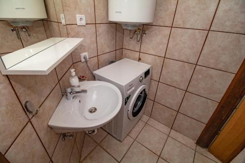 a bathroom with a washing machine and a sink at Guest house Otto in Punat