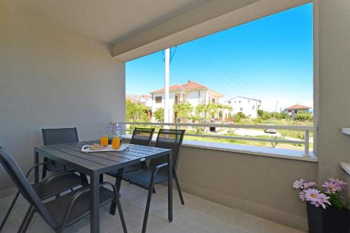 a balcony with a table and chairs and a large window at sunshine in Trogir